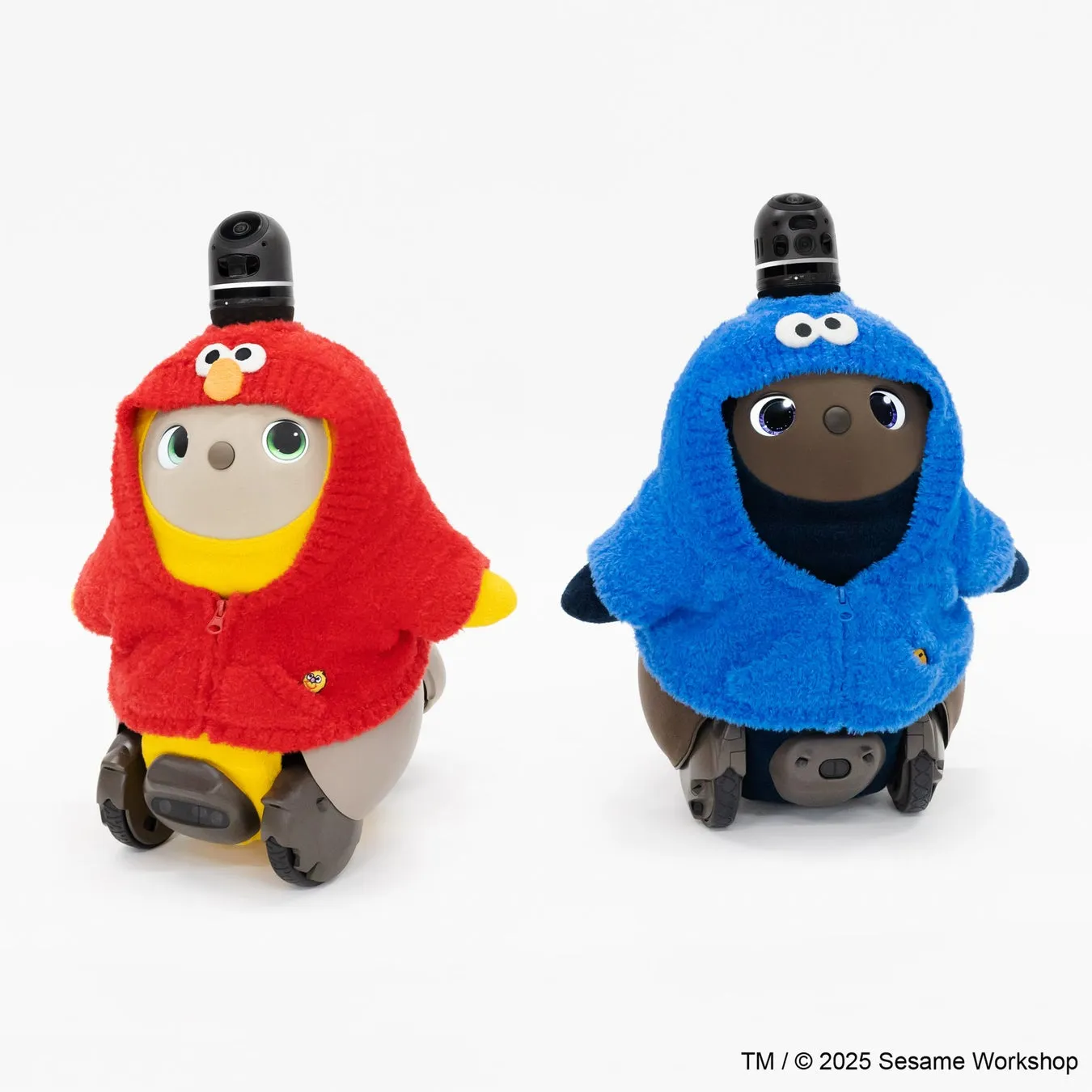 2体のロボットがセサミストリートのキャラクターのコスチュームを着ている写真です。左のロボットはエルモのコスチューム、右のロボットはクッキーモンスターのコスチュームを着ています。背景は白です。