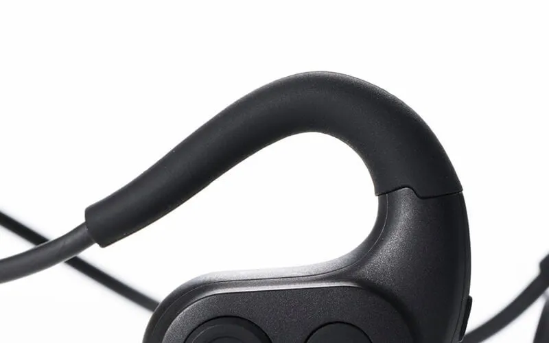 黒いイヤホンのクローズアップ画像です。イヤホンは黒いゴム製のイヤーフックとイヤーピースを備え、白い背景に配置されています。