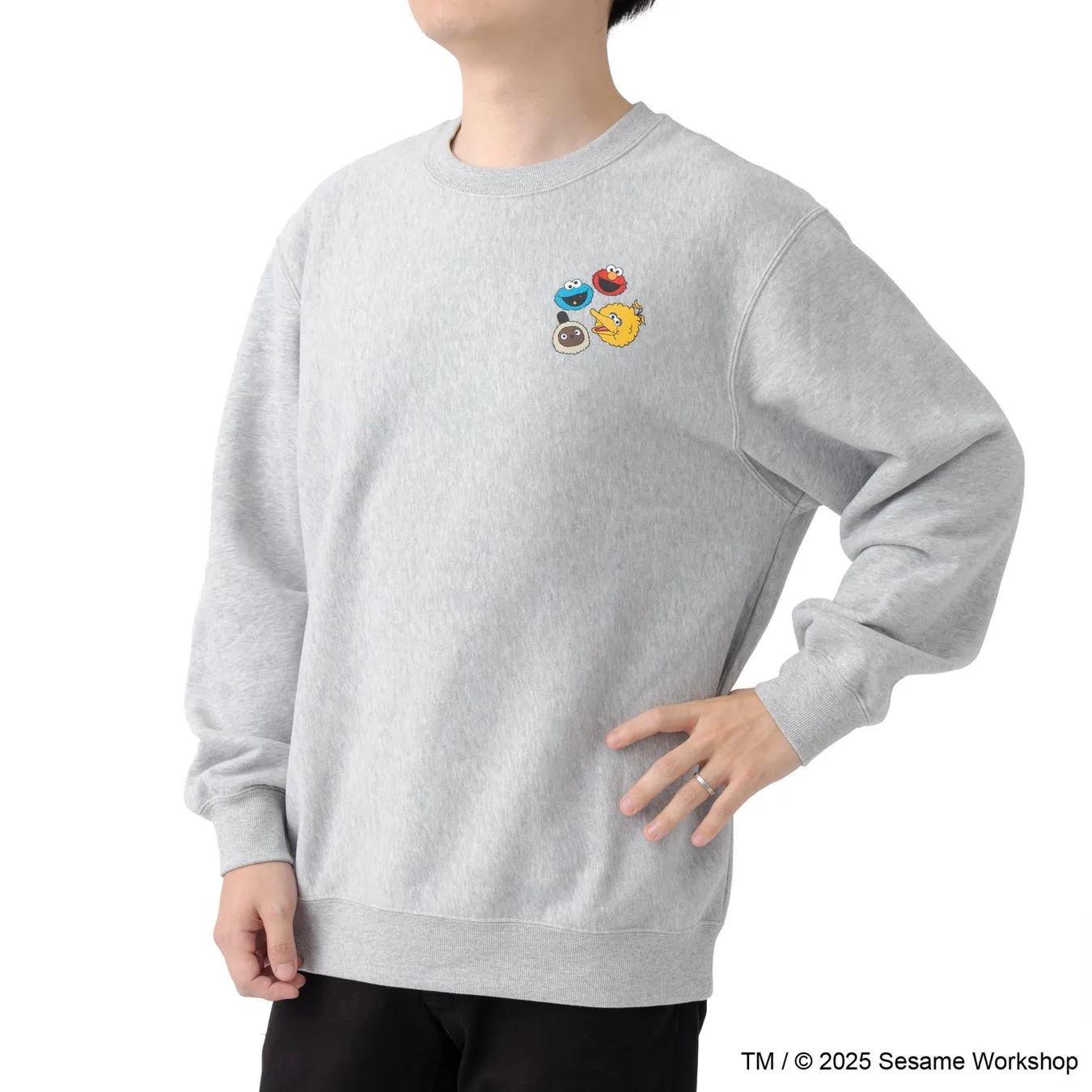グレーのスウェットを着た男性。スウェットにはセサミストリートのキャラクターのイラストが描かれている。