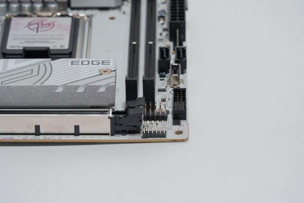 x16スロットのロックピン横にあるのはフロントパネル用のピンヘッダ（ロックを挟んで奥側）とTPM用のピンヘッダ（ロックを挟んで手前側）